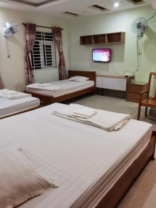 um quarto com 3 camas e uma televisão de ecrã plano em MOTEL WIN - PHÁT em Bien Hoa