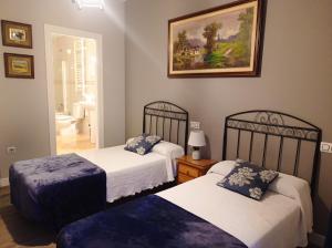a bedroom with two beds and a painting on the wall at Hospedaje Don Pelayo in Gijón