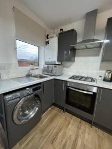 a kitchen with a washing machine and a sink at Modern 2 Bed Flat In Derby City in Derby