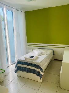 a bed in a room with a green wall at Cabo Frio Familiar Toca de Gente Feliz in Cabo Frio +53 photos
