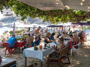 a group of people sitting at tables on a beach at Boonsong Guest House in Khao Tao