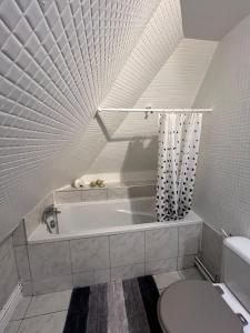 La salle de bains est pourvue d'une baignoire et de toilettes. dans l'établissement Spacieux appartement jardin, BBQ, vue sur mer, Trouville, à Trouville-sur-Mer