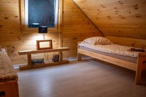 a bedroom in a log cabin with a bed and a table at Zagajnik Białowieża in Białowieża