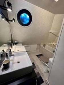 La salle de bains est pourvue d'un lavabo, de toilettes et d'une fenêtre. dans l'établissement Spacieux appartement jardin, BBQ, vue sur mer, Trouville, à Trouville-sur-Mer