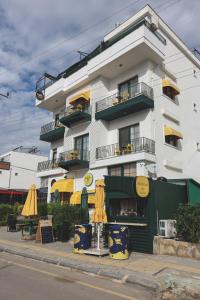 ein weißes Gebäude mit gelben Sonnenschirmen davor in der Unterkunft Limon Inn Hotel, Taşucu in Tasucu