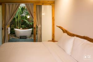 a bedroom with a bed and a bathroom with a tub at Tổ Boutique Garden in La Gi