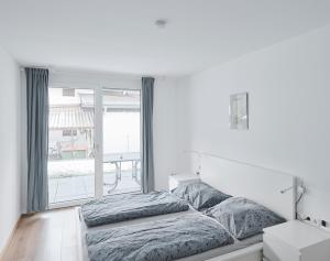 a white bedroom with a bed and a large window at Wohnen in Wattens Top 3 in Wattens