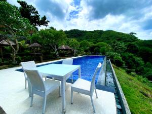 a table and chairs sitting next to a swimming pool at Ara Artati Lombok bungalows and Restaurant in Selong Belanak