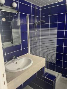 y baño de azulejos azules con lavabo y ducha. en Hôtel La Pinède en Saint-Marcellin-lès-Vaison
