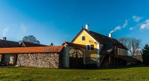 a yellow building with a stone wall next to a house at Ekofarma Polná in Hazlov