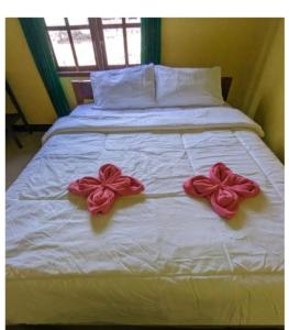 two pink bows are on a white bed at Mushtinal Guest House in Ende