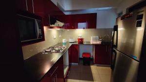 a kitchen with red cabinets and a stainless steel refrigerator at Cozy 2 BR Apartment with pool by Ceylon Vacation in Colombo