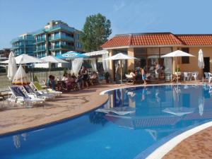 a swimming pool with chairs and umbrellas next to a building at Apart Hotel Kasandra in Sunny Beach
