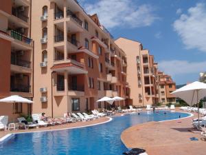 a swimming pool in front of a building with chairs and umbrellas at Apart Hotel Kasandra in Sunny Beach