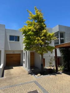 a tree in front of a house with a garage at Luxury Townhouse in Stellenbosch CENTRAL (BACK-UP POWER) in Stellenbosch