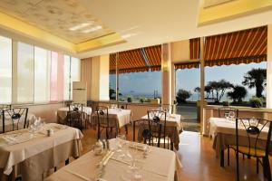 a restaurant with white tables and chairs and windows at Hotel Delfino in Laigueglia