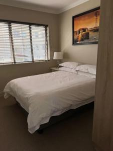 a bedroom with a large white bed with two windows at Luxury Townhouse in Stellenbosch CENTRAL (BACK-UP POWER) in Stellenbosch