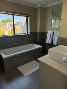 baño con bañera, lavabo y ventana en Luxury Townhouse in Stellenbosch CENTRAL (BACK-UP POWER), en Stellenbosch