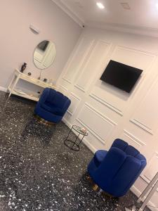 due sedie blu davanti a un muro con uno specchio di Oceania Hotels Napoli a Napoli