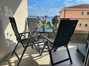 a table and chairs on a balcony with a vase of flowers at Luxury and Spa App F in Makarska