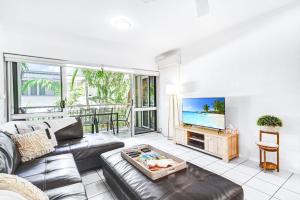 a living room with a couch and a tv at Cozie Homes - Mantaray on Macrossan in Port Douglas