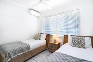 a bedroom with two beds and a window at Cozie Homes - Mantaray on Macrossan in Port Douglas +7 photos