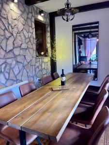 a dining room with a wooden table and a bottle of wine at Camp Hotel Lake Views in Plav