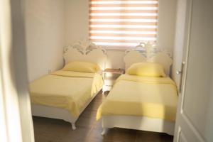 two twin beds in a room with a window at Apartmani ELEGANCE Tuzla in Tuzla