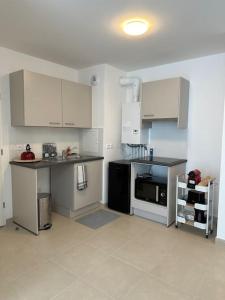 a kitchen with white cabinets and a black appliances at Appartement - Tournan en Brie a 20min de Disneyland in Tournan-en-Brie