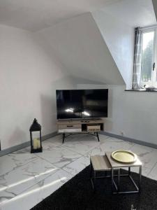 T2 Chaleureux et cocooning في Quintin: غرفة معيشة مع تلفزيون بشاشة مسطحة وطاولة