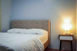 ein Schlafzimmer mit einem Bett und einem Nachttisch mit einer Lampe in der Unterkunft RQ Cozy Two Bedroom House @ La Cassandra, Wifi & Netflix in General Santos