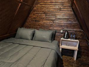 a bed in a room with a wooden wall at Triangular house and hot spring in Kubupenlokan