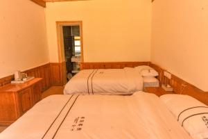a room with three beds and a window at Tibet Guesthouse 虎跳峡卓玛客栈 in Shangri-La