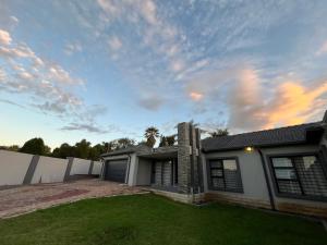 a house with a yard with a cloudy sky at The Benjamin Accomodation in Edenvale