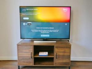 a flat screen tv sitting on a wooden entertainment center at Pass the Keys King Bed Family Home With Parking WM Discounts in Manchester