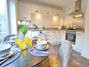 a kitchen with a wooden table with chairs and orange juice at Pass the Keys King Bed Family Home With Parking WM Discounts in Manchester