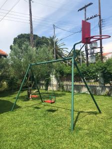 a swing set in a yard with a basketball hoop at O&A By the Sea in Polykhrono