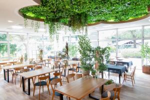 a restaurant with tables and chairs and plants at BIO-RESORT HOTEL & SPA O Park OGOSE in Ogose