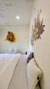 1 dormitorio con 1 cama blanca grande con flores en la pared en Kashi Village Home Stay en Varanasi