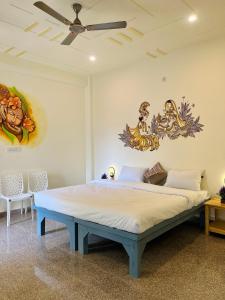 een bed in een kamer met schilderijen aan de muur bij Kashi Village Home Stay in Varanasi