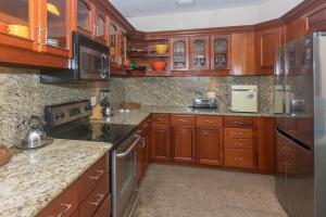 a kitchen with wooden cabinets and a refrigerator at Lawson Rock - Angelfish 201 condo in Roatan