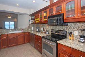 a kitchen with wooden cabinets and a stove top oven at Lawson Rock - Angelfish 201 condo in Roatan