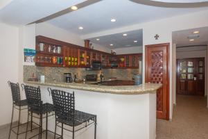 a kitchen with a bar with chairs and cabinets at Lawson Rock - Angelfish 201 condo in Roatan