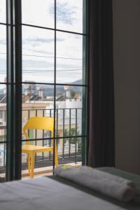 a bedroom with a yellow chair and a window at Limon Inn Hotel, Taşucu in Tasucu