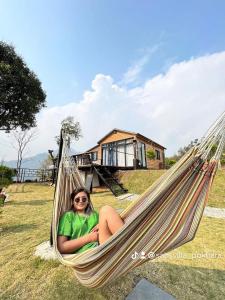 a woman sitting in a hammock in a yard at (Sab’s villa )Forest cabin in Pokhara