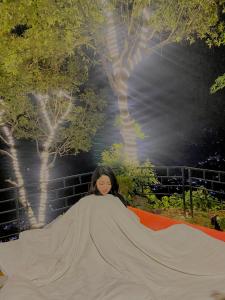 uma mulher deitada num tapete laranja com um grande cobertor em (Sab’s villa )Forest cabin em Pokhara