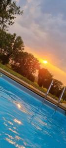 a swimming pool with a sunset in the background at Maison de Vacances avec Piscine Privée en Dordogne in Boisse