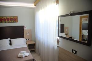 una camera d'albergo con letto e specchio di Hotel Dei Tartari a Guidonia