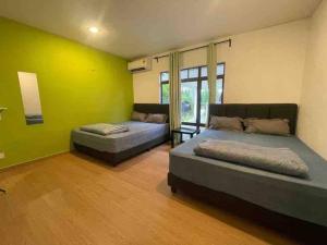 una camera da letto con due letti e una parete verde di A’famosa Moments villa 924 covered Bbq KTV pool a Kampong Alor Gajah Altre 45 foto
