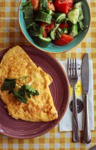 a plate with a omelet and a bowl of salad at Limon Inn Hotel, Taşucu in Tasucu